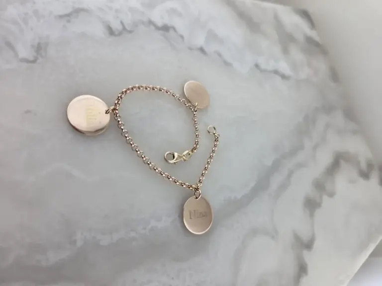 A silver necklace with multiple round pendants on a white textured surface.