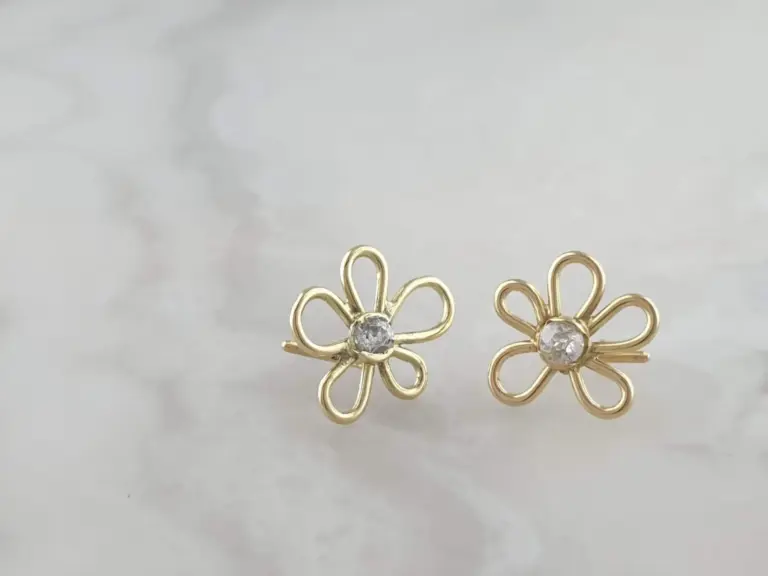 Gold-tone floral earrings with a clear gemstone center, displayed against a plain light-colored background.