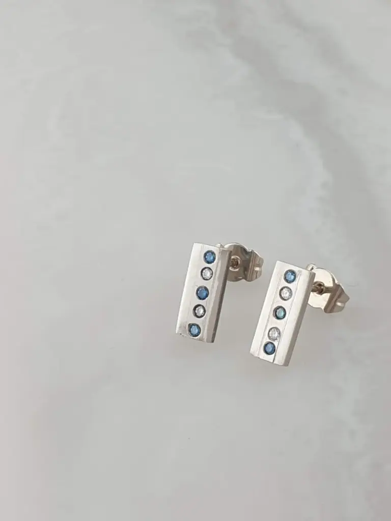 Close-up of two LEGO door hinge pieces with blue and clear decorative elements, set against a plain light background.