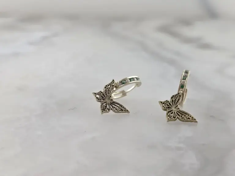 Silver earrings with butterfly designs resting on a white surface.