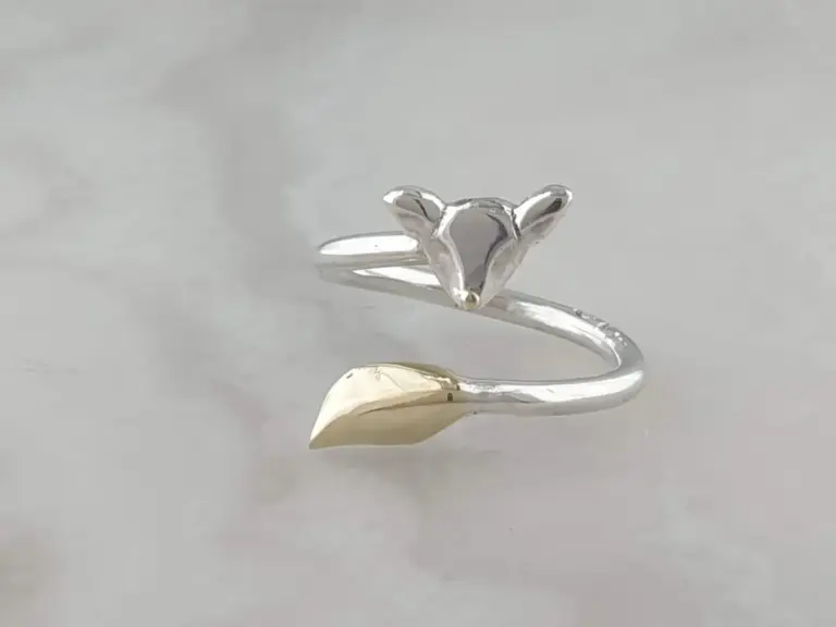Silver ring with a heart-shaped design and decorative ears, displayed on a white surface.