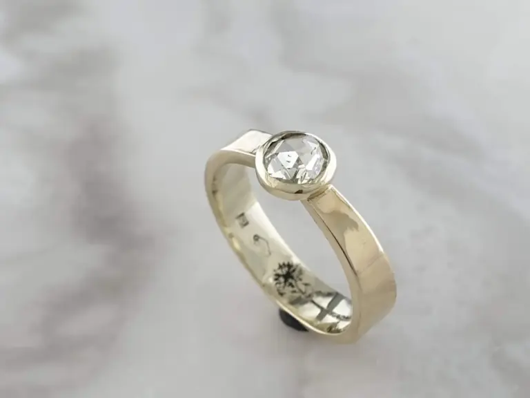 A diamond ring with a large round cut diamond set in a silver band, placed on a white background.