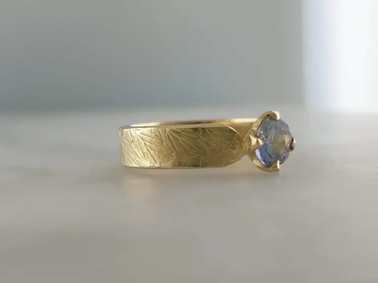 Gold ring with a large, round, cut gemstone set in a prong setting.