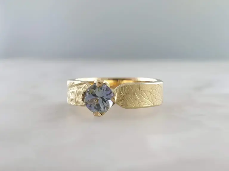 Close-up of a gold ring with a large heart-shaped gemstone set in a prong setting.