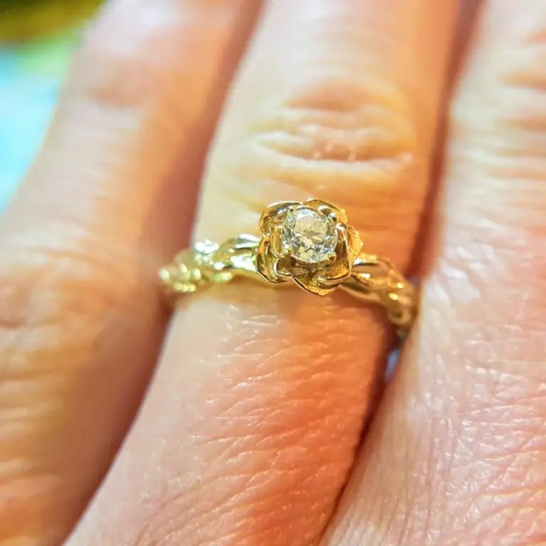 Close-up of a person's finger with a gold ring featuring a large clear gemstone.