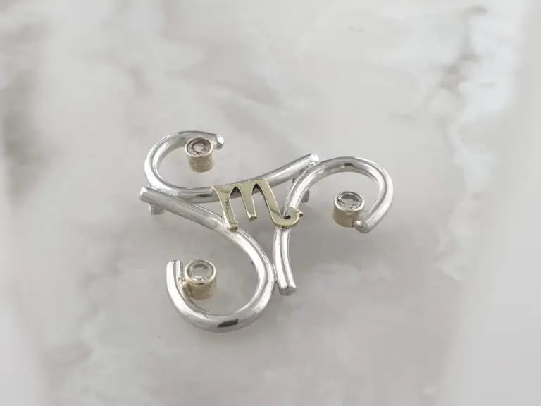 Silver jewelry tree displaying earrings and rings, with a shiny reflective surface.