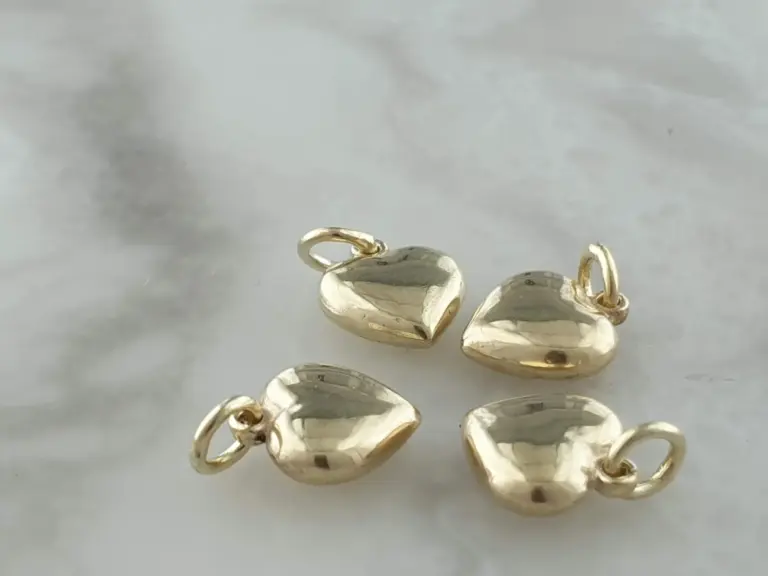 Close-up of gold heart-shaped earrings on a white surface.
