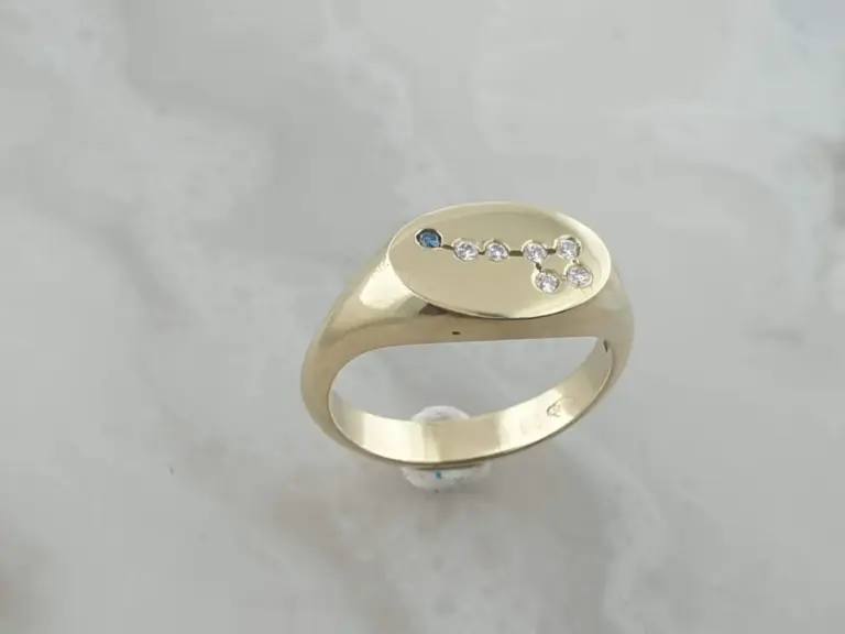 Gold ring with small diamonds and a small blue gemstone in a curved design