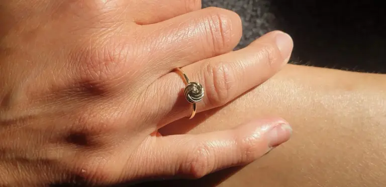 Close-up of a hand wearing a ring with a metallic swirl design on the ring finger.