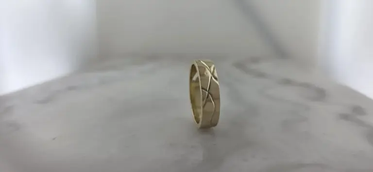 Silver ring with a nature-inspired leaf or branch design, standing upright on a white surface with a simple, plain background.