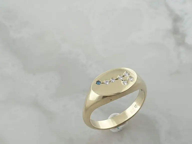 Gold ring with embedded small diamonds and a small blue gemstone set in the design.
