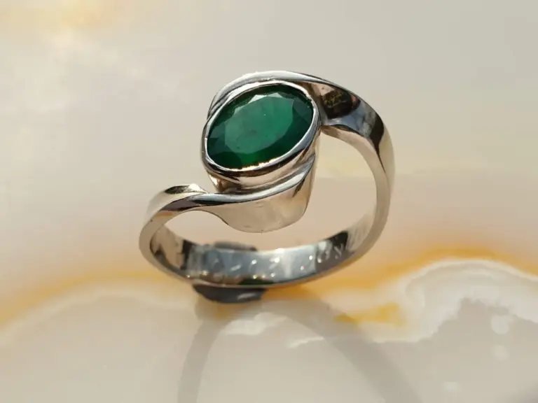 A silver ring with a large, oval-shaped green gemstone.