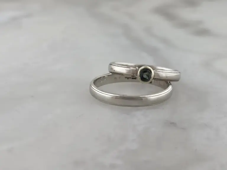 Silver rings with white gold and black gemstones, resting on a plain white surface.