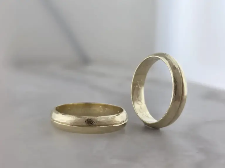 Close-up of three silver rings with engravings on a plain light background.