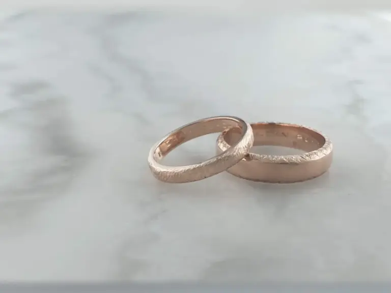 Close-up of two textured silver rings placed on a light surface.