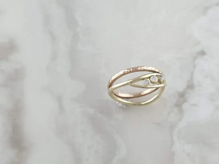 Close-up of a gold ring with three small diamonds on a reflective surface.