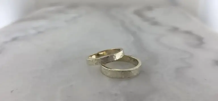 Two silver hammered wedding bands on a white surface.