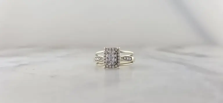 Silver ring with a rectangular cluster of diamonds surrounded by smaller diamonds on a white marble surface.